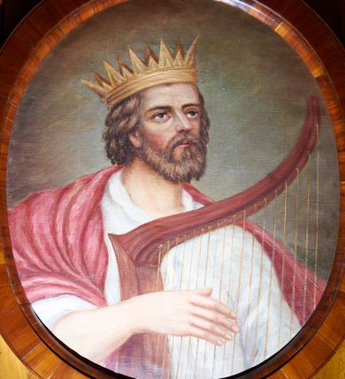 Zdjęcie nr 1: Obraz w kształcie owalu z przedstawieniem króla Dawida, grającego prawą ręką na czerwonej harfie, ukazanego w popiersiu, zwróconego lekko w lewą stronę. Głowa uniesiona, skierowana w lewo. Twarz okolona krótkim, jasnobrązowym zarostem, nos długi, oczy ciemne. Ubrany jest w białą suknię oraz purpurowy płaszcz okrywający prawe ramię, na głowie ma założoną złotą koronę otwartą. Tło jasnobrązowe, rozświetlone wokół głowy. Rama drewniana, fornirowana, politurowana.