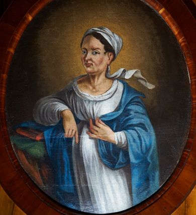 Zdjęcie nr 1: Obraz w kształcie stojącego owalu, przedstawiający św. Elżbietę, ukazaną do wysokości kolan, zwróconą trzy czwarte w prawo, która prawą ręką opiera się o występ skalny, a lewą dłonią podtrzymuje brzeg płaszcza. Twarz o wyraźnych rysach, migdałowych oczach i spiczastym nosie. Włosy ciemnobrązowe, schowane pod białą chustką, której jeden koniec spływa nad jej lewym ramieniem. Ubrana jest w białą suknię oraz niebieski płaszcz. Na występie skalnym leży czerwona księga. Tło ciemnobrązowe, rozświetlone wokół głowy świętej. Rama drewniana, fornirowana, politurowana.
