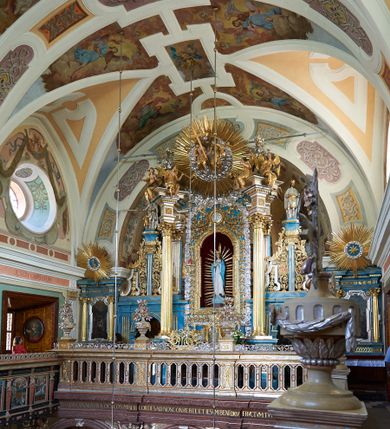 Zdjęcie nr 1: Ołtarz architektoniczny, jednokondygnacyjny, jednoosiowy. Mensa sarkofagowa z dwiema fornirowanymi płycinami w polu; niesymetryczna z prawym bokiem przylegającym do ściany. Nastawa ołtarzowa wsparta na łamanym cokole, ujęta dwoma pilastrami oraz parą kolumn z kanelowanymi i złoconymi trzonami o kompozytowych kapitelach. Podpory wspierają wyłamane belkowanie i silnie profilowany gzyms. Ołtarz zwieńczony jest promienistą glorią, w której w niebieskim polu, otoczonym obłokami znajduje się kwiat róży. W polu głównym w ramie w kształcie stojącego prostokąta z uszakami o wklęsłych górnych narożach umieszczony jest obraz „Pokłon pasterzy”. Struktura polichromowana w kolorze jasnoniebieskim; ornamentyka, detale i profilowania złocone oraz srebrzone. 




