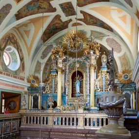 Zdjęcie nr 1: Ołtarz architektoniczny, jednokondygnacyjny, jednoosiowy. Mensa sarkofagowa z dwiema fornirowanymi płycinami w polu; niesymetryczna z prawym bokiem przylegającym do ściany. Nastawa ołtarzowa wsparta na łamanym cokole, ujęta dwoma pilastrami oraz parą kolumn z kanelowanymi i złoconymi trzonami o kompozytowych kapitelach. Podpory wspierają wyłamane belkowanie i silnie profilowany gzyms. Ołtarz zwieńczony jest promienistą glorią, w której w niebieskim polu, otoczonym obłokami znajduje się kwiat róży. W polu głównym w ramie w kształcie stojącego prostokąta z uszakami o wklęsłych górnych narożach umieszczony jest obraz „Pokłon pasterzy”. Struktura polichromowana w kolorze jasnoniebieskim; ornamentyka, detale i profilowania złocone oraz srebrzone. 




