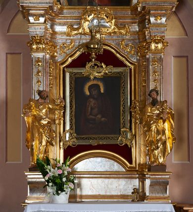 Zdjęcie nr 5: Rzeźba drążona, ustawiona na prostopadłościennym cokole. Figura ukazana frontalnie z głową skierowaną w prawą stronę; lewą ręką przytrzymuje opartą na biodrze księgę, prawa spoczywa na wysokości pasa. Twarz pociągła, szczupła, oczy duże, płytko rzeźbione, nos prosty, usta pełne; okolona długą brodą. Włosy krótkie, kręcone, poruszone. Święty ubrany jest w suknię z kołnierzykiem, z wąskimi rękawami z wywiniętym brzegiem, przepasaną w talii; tkanina ściśle przylega do ciała, jest delikatnie drapowana u spodu. Na lewe ramię ma narzucony płaszcz, opadający na plecy i bok, zawinięty na prawej nodze; tkanina silnie drapowana, z wywiniętym, skręconym brzegiem. Polichromia naturalistyczna w odsłoniętych partiach ciała, szaty i atrybuty złocone.