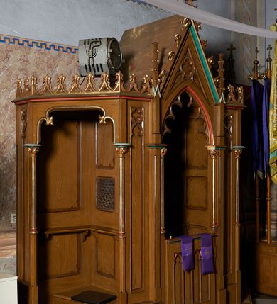 Zdjęcie nr 2: Konfesjonał na planie prostokąta o ściętych narożach, z klęcznikami ograniczonymi krótkimi ściankami ujętymi kolumienkami. Część środkowa z drzwiczkami dekorowanymi blendami i ostrołukową arkadą ujęta od środka maswerkiem wspartą na kolumienkach, zwieńczoną wimpergą z krzyżem, ujętą pinaklami. Gzyms wieńczący ozdobiony ażurowo potraktowanymi żabkami. Całość struktury w odcieniu ciemnego drewna, profile złocone oraz polichromowane na czerwono i zielono.