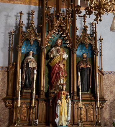 Zdjęcie nr 1: Nastawa ołtarzowa architektoniczna, jednokondygnacyjna, trójosiowa, ze zwieńczeniem. Ołtarz drewniany, skrzyniowy, mensa drewniana. Antepedium z narożami wypełnionymi ćwierćkolumienkami, dekorowane czterema blendami, z czworoliściem z gorejącym sercem pośrodku. Tabernakulum w formie prostopadłościennej szafki, ujęte w narożach kolumienkami dźwigającymi gzyms o kształcie łuku ostrego nadwieszonego dekorowanego żabkami i zwieńczonego pinaklem. Drzwiczki w formie stojącego prostokąta zamkniętego łukiem ostrym, zdobione płaskorzeźbionym motywem winnej latorośli, kłosów zbóż i monogramem IHS. Predella nastawy dekorowana blendami z malowaną dekoracją w formie winnego grona. 
Retabulum ołtarzowe w postaci trzech nisz zamkniętych łukami ostrymi, ujętych kolumienkami o kapitelach dekorowanych stylizowanymi rozetami i  dźwigającymi pinakle z żabkami i kwiatonami. Środkowa nisza zamknięta łukiem ostrym z krenelażem, ponad którym ażurowa konstrukcja utworzona z wimperg i pinakli, dekorowana żabkami i kwiatonami. Nisze boczne zwieńczone przeplatającymi się żebrami, dekorowanymi w polach rozetami i pinaklami zakończonymi kwiatonami. Zwieńczenie w formie ażurowej konstrukcji utworzonej z pinakli połączonych łukami przyporowymi, dekorowanymi krenelażem i żabkami, środkowy pinakiel najwyższy, zwieńczony krzyżem. W niszy środkowej figura Najświętsze Serce Jezusa, w bocznych: św. Teresa z Avila po lewej i św. Andrzej Bobola po prawej stronie. Nastawa ujęta uszami utworzonymi z przypór z pinaklami.
Ołtarz w kolorze ciemnego drewna, blendy i nisze polichromowane na niebiesko i zielono, profile, detale i ornamenty złocone.
