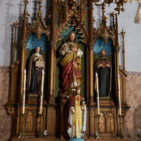 Zdjęcie nr 1: Nastawa ołtarzowa architektoniczna, jednokondygnacyjna, trójosiowa, ze zwieńczeniem. Ołtarz drewniany, skrzyniowy, mensa drewniana. Antepedium z narożami wypełnionymi ćwierćkolumienkami, dekorowane czterema blendami, z czworoliściem z gorejącym sercem pośrodku. Tabernakulum w formie prostopadłościennej szafki, ujęte w narożach kolumienkami dźwigającymi gzyms o kształcie łuku ostrego nadwieszonego dekorowanego żabkami i zwieńczonego pinaklem. Drzwiczki w formie stojącego prostokąta zamkniętego łukiem ostrym, zdobione płaskorzeźbionym motywem winnej latorośli, kłosów zbóż i monogramem IHS. Predella nastawy dekorowana blendami z malowaną dekoracją w formie winnego grona. 
Retabulum ołtarzowe w postaci trzech nisz zamkniętych łukami ostrymi, ujętych kolumienkami o kapitelach dekorowanych stylizowanymi rozetami i  dźwigającymi pinakle z żabkami i kwiatonami. Środkowa nisza zamknięta łukiem ostrym z krenelażem, ponad którym ażurowa konstrukcja utworzona z wimperg i pinakli, dekorowana żabkami i kwiatonami. Nisze boczne zwieńczone przeplatającymi się żebrami, dekorowanymi w polach rozetami i pinaklami zakończonymi kwiatonami. Zwieńczenie w formie ażurowej konstrukcji utworzonej z pinakli połączonych łukami przyporowymi, dekorowanymi krenelażem i żabkami, środkowy pinakiel najwyższy, zwieńczony krzyżem. W niszy środkowej figura Najświętsze Serce Jezusa, w bocznych: św. Teresa z Avila po lewej i św. Andrzej Bobola po prawej stronie. Nastawa ujęta uszami utworzonymi z przypór z pinaklami.
Ołtarz w kolorze ciemnego drewna, blendy i nisze polichromowane na niebiesko i zielono, profile, detale i ornamenty złocone.
