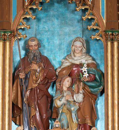 Zdjęcie nr 5: Nastawa ołtarzowa architektoniczna, jednokondygnacyjna, trójosiowa, ze zwieńczeniem. Ołtarz drewniany, skrzyniowy, mensa drewniana z marmurowym portatylem. Antepedium dekorowane czterem blendami, z czworoliściem z monogramem IHS w centrum. Tabernakulum w formie prostopadłościanu, dwukondygnacyjne, ze zwieńczeniem, na szerokiej podstawie. W dolnej kondygnacji dwoje drzwi dekorowanych ostrołukowymi blendami i przedzielonych służką. Wyżej tron wystawienia trójosiowy, w postaci trzech nisz zamkniętych łukiem ostrym, ujętych służkami dźwigającymi pinakle. Oś środkowa wyższa, z dwuskrzydłowymi drzwiczkami przedzielonymi służką i dekorowanymi płaskorzeźbioną winną latoroślą z kłosami zbóż. W niszach bocznych figury adorujących aniołów. Całość zwieńczona postumentem na relikwie. Retabulum ołtarzowe w postaci trzech nisz zamkniętych łukami ostrymi z ażurowym fryzem arkadkowym, dekorowanym po bokach blendami; osie wydzielone służkami, podwójnymi w osi środkowej, dźwigającymi pinakle z żabkami i kwiatonami. Osie zwieńczone ażurowymi wieżyczkami przeprutymi łukami trójlistnymi ostrymi, których pierwszą kondygnację kończy łuk odwrócony,  dekorowany pinaklami i żabkami, zwieńczony kwiatonem. Wieżyczki ujmują spływy z żabkami. Predella zdobiona blendami. W centralnej niszy grupa rzeźbiarska Rodziny Marii, w bocznych figury św. Piotra po lewej i św. Pawła po prawej stronie. Ołtarz w kolorze ciemnego drewna, blendy i nisze polichromowane na niebiesko i czerwono, profile, detale i ornamenty złocone. 