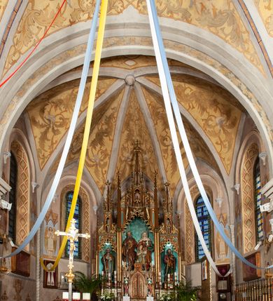 Zdjęcie nr 3: Nastawa ołtarzowa architektoniczna, jednokondygnacyjna, trójosiowa, ze zwieńczeniem. Ołtarz drewniany, skrzyniowy, mensa drewniana z marmurowym portatylem. Antepedium dekorowane czterem blendami, z czworoliściem z monogramem IHS w centrum. Tabernakulum w formie prostopadłościanu, dwukondygnacyjne, ze zwieńczeniem, na szerokiej podstawie. W dolnej kondygnacji dwoje drzwi dekorowanych ostrołukowymi blendami i przedzielonych służką. Wyżej tron wystawienia trójosiowy, w postaci trzech nisz zamkniętych łukiem ostrym, ujętych służkami dźwigającymi pinakle. Oś środkowa wyższa, z dwuskrzydłowymi drzwiczkami przedzielonymi służką i dekorowanymi płaskorzeźbioną winną latoroślą z kłosami zbóż. W niszach bocznych figury adorujących aniołów. Całość zwieńczona postumentem na relikwie. Retabulum ołtarzowe w postaci trzech nisz zamkniętych łukami ostrymi z ażurowym fryzem arkadkowym, dekorowanym po bokach blendami; osie wydzielone służkami, podwójnymi w osi środkowej, dźwigającymi pinakle z żabkami i kwiatonami. Osie zwieńczone ażurowymi wieżyczkami przeprutymi łukami trójlistnymi ostrymi, których pierwszą kondygnację kończy łuk odwrócony,  dekorowany pinaklami i żabkami, zwieńczony kwiatonem. Wieżyczki ujmują spływy z żabkami. Predella zdobiona blendami. W centralnej niszy grupa rzeźbiarska Rodziny Marii, w bocznych figury św. Piotra po lewej i św. Pawła po prawej stronie. Ołtarz w kolorze ciemnego drewna, blendy i nisze polichromowane na niebiesko i czerwono, profile, detale i ornamenty złocone. 