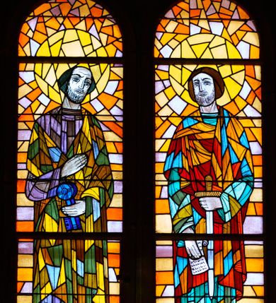 Zdjęcie nr 2: Witraże w formie stojącego prostokąta zamkniętego łukiem pełnym. Każdy z nich podzielony jest na dwa mniejsze prostokąty zamknięte półkoliście (o trzech kwaterach każdy) z postaciami świętych, powyżej których w podłuczu medalion z popiersiem kolejnego świętego. Przyłucza wypełniają dekoracyjne trójkąty. Ściana wschodnia nawy głównej: 1. Święci Jakub i Jan, zwróceni do wewnątrz, na abstrakcyjnym tle. Pod nogami św. Jakuba leży miecz. Święty Jan trzyma w ręku zwój. U spodu podpisy „ŚW(IĘTY) JAKUB / STARSZY APOSTOŁ” i „APOSTOŁ / ŚW(IĘTY) JAN”. Ponad nimi widnieje wpisana w koło półpostać św. Augustyna z podpisem „ŚW. AUGUSTYN”. Kolorystyka ciepła, tło w kolorach z przewagą barwy pomarańczowej, postacie wyodrębnione intensywną kolorystyką z dominacją zieleni. 2. Święci Andrzej i Filip zwróceni do wewnątrz, na abstrakcyjnym tle. Za postaciami krzyże męczeństwa. U spodu podpisy „APOSTOŁ / ŚW(IĘTY) ANDRZEJ”, „APOSTOŁ / ŚW(IĘTY) FILIP”. Ponad nimi wpisana w koło półpostać św. Bonawentury z podpisem „ŚW(IĘTY) BONAWENTURA”. Tło z przewagą zieleni i czerwieni. Ściana zachodnia nawy głównej: 1. Święci Piotr i Paweł, zwróceni do wewnątrz, na abstrakcyjnym tle. Piotr trzyma klucze, u jego stóp krzyż; Paweł trzyma miecz i zwój, u jego stóp miecz. W dolnym rogu podpisy „APOSTOŁ / ŚW(IĘTY) PIOTR”, „APOSTOŁ / ŚW(IĘTY) PAWEŁ”. Ponad nimi widnieje wpisany w koło wizerunek św. Grzegorza z podpisem „ŚW(IĘTY) GRZE/GORZ”. Kolorystyka z przewagą żółcieni i zieleni. 2. Święci Bartłomiej i Mateusz na abstrakcyjnym tle. Bartłomiej zwrócony frontalnie z lewą ręką złożoną na piersi i prawą uniesiona w górę; u spodu, za postacią miecz. Mateusz z głową zwróconą do wewnątrz, z dłońmi skrzyżowanymi na piersi; u spodu włócznia. W dolnych rogach podpisy: „APOSTOŁ / ŚW(IĘTY) BARTŁOMIEJ” i „APOSTOŁ / ŚW(IĘTY) MATEUSZ”. Ponad nim wpisana w koło półpostać św. Tomasza, z podpisem „ŚW(IĘTY) TOMASZ”. Kolorystyka z przewagą niebieskiego i pomarańczowego.