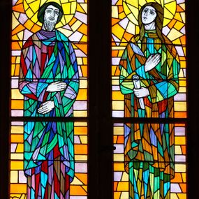 Zdjęcie nr 1: Witraże w formie stojącego prostokąta zamkniętego łukiem pełnym. Każdy z nich podzielony jest na dwa mniejsze prostokąty zamknięte półkoliście (o trzech kwaterach każdy) z postaciami świętych, powyżej których w podłuczu medalion z popiersiem kolejnego świętego. Przyłucza wypełniają dekoracyjne trójkąty. Ściana wschodnia nawy głównej: 1. Święci Jakub i Jan, zwróceni do wewnątrz, na abstrakcyjnym tle. Pod nogami św. Jakuba leży miecz. Święty Jan trzyma w ręku zwój. U spodu podpisy „ŚW(IĘTY) JAKUB / STARSZY APOSTOŁ” i „APOSTOŁ / ŚW(IĘTY) JAN”. Ponad nimi widnieje wpisana w koło półpostać św. Augustyna z podpisem „ŚW. AUGUSTYN”. Kolorystyka ciepła, tło w kolorach z przewagą barwy pomarańczowej, postacie wyodrębnione intensywną kolorystyką z dominacją zieleni. 2. Święci Andrzej i Filip zwróceni do wewnątrz, na abstrakcyjnym tle. Za postaciami krzyże męczeństwa. U spodu podpisy „APOSTOŁ / ŚW(IĘTY) ANDRZEJ”, „APOSTOŁ / ŚW(IĘTY) FILIP”. Ponad nimi wpisana w koło półpostać św. Bonawentury z podpisem „ŚW(IĘTY) BONAWENTURA”. Tło z przewagą zieleni i czerwieni. Ściana zachodnia nawy głównej: 1. Święci Piotr i Paweł, zwróceni do wewnątrz, na abstrakcyjnym tle. Piotr trzyma klucze, u jego stóp krzyż; Paweł trzyma miecz i zwój, u jego stóp miecz. W dolnym rogu podpisy „APOSTOŁ / ŚW(IĘTY) PIOTR”, „APOSTOŁ / ŚW(IĘTY) PAWEŁ”. Ponad nimi widnieje wpisany w koło wizerunek św. Grzegorza z podpisem „ŚW(IĘTY) GRZE/GORZ”. Kolorystyka z przewagą żółcieni i zieleni. 2. Święci Bartłomiej i Mateusz na abstrakcyjnym tle. Bartłomiej zwrócony frontalnie z lewą ręką złożoną na piersi i prawą uniesiona w górę; u spodu, za postacią miecz. Mateusz z głową zwróconą do wewnątrz, z dłońmi skrzyżowanymi na piersi; u spodu włócznia. W dolnych rogach podpisy: „APOSTOŁ / ŚW(IĘTY) BARTŁOMIEJ” i „APOSTOŁ / ŚW(IĘTY) MATEUSZ”. Ponad nim wpisana w koło półpostać św. Tomasza, z podpisem „ŚW(IĘTY) TOMASZ”. Kolorystyka z przewagą niebieskiego i pomarańczowego.