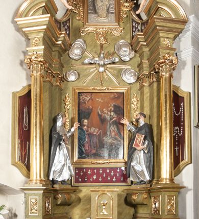 Zdjęcie nr 1: Nastawa ołtarzowa jednokondygnacyjna, jednoosiowa, ze zwieńczeniem i uszakami ustawiona na wysokim, dwudzielnym cokole. Przed nim prostopadłościenna mensa ołtarzowa z malowanym antepedium w kształcie leżącego prostokąta z przedstawieniem Ucieczki do Egiptu wzorowanym na kompozycji Giotta di Bondone. Na mensie prostopadłościenne tabernakulum zwieńczone gzymsem z drzwiczkami w kształcie stojącego prostokąta zamkniętego łukiem pełnym dekorowanymi kielichem z hostią. Kondygnacja nastawy flankowana jest przez ustawione skośnie do zewnątrz, zdwojone filary i stojące przed nimi, pozłacane kolumny o głowicach kompozytowych. W części centralnej znajduje się wnęka otoczona złotą, profilowaną ramą z rokokowym ornamentem, a w niej obraz Matki Boskiej z Dzieciątkiem, wymiennie ze sceną Zwiastowania, adorowany przez dwie flankujące go rzeźby – świętej zakonnicy po lewej i świętego zakonnika z księgą po prawej stronie. Poniżej pola obrazowego rama w kształcie leżącego prostokąta, po dwóch stronach kondygnacji uszaki w formie gablot w kształcie zbliżonym do trapezu, o wklęsło-wypukłych bokach. Wszystkie trzy wypełniają wota dziękczynne należące do obrazu Matki Boskiej. Kolumny i filary dźwigają belkowanie z rocaille'owym ornamentem na fryzie, zakończone mocno wysuniętym gzymsem, na którym umieszczono fragmenty przerwanego przyczółka. Na nim posadowiono putta trzymające kartusze, z napisami: „AVE” po lewej stronie i „MARIA” po prawej. Nad polem kondygnacji, na wysokości belkowania i gzymsu, znajduje się rzeźba gołębicy Ducha Świętego otoczona złotymi promieniami i czterema obłokami. Zwieńczenie zamknięte łukiem nadwieszonym mieści obraz z przedstawieniem Matki Boskiej Niepokalanie Poczętej w złotej profilowanej ramie, otoczony z trzech stron bujnym rocaille’owym ornamentem. Całość wieńczy kartusz utworzony z ornamentu rocaille’owego z monogramem maryjnym. Struktura polichromowana w imitacje marmoryzacji w kolorze zielonym, profile, detale i ornamenty złocone i srebrzone. 