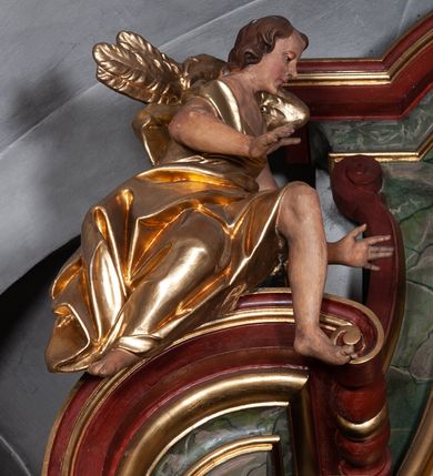 Zdjęcie nr 21: Retabulum jednokondygnacyjne, trójosiowe ze zwieńczeniem i bramkami. Mensa ołtarzowa z malowanym antepedium przedstawiającym scenę Ostatniej Wieczerzy według Leonarda da Vinci. Na mensie ustawione pozłacane tabernakulum w formie prostopadłościennej z częścią środkową w ozdobnej oprawie utworzonej przez dwa ukośnie dostawione filary ze spływami wolutowymi. Między nimi wypukłe w dolnej części drzwiczki dekorowane kielichem z hostią ponad kiśćmi winogron i między kłosami zbóż. Powyżej nisza konchowa wypełniona glorią, której koncha ozdobiona jest muszlą z rocaille’owym grzebieniem. Na wolutach osadzone adorujące krzyż putta. Część centralna nastawy flankowana kolumnami z głowicami jońskimi i ornamentem rokokowym. W polu w profilowanej złotej ramie przedstawienie koronacji Marii przez Trójcę Świętą. Drewniana konstrukcja skrzydeł bocznych tworzy ramę dla dwóch rzeźb ustawionych na bramkach, na odcinkach gzymsu rozszerzających się ku górze, które tworzą cokoły ozdobione w dolnej części rokokową muszlą. Po prawej stronie znajduje się rzeźba przedstawiająca św. Stanisława z Piotrowinem, po lewej św. Wojciecha. Obie rzeźby biskupów są tej samej wielkości, wypełniają prześwity w bocznych skrzydłach, w tle ozdobionych rocaille’owym ornamentem. Zewnętrzne płaszczyzny skrzydeł bocznych zdobi złota winorośl, a wewnętrzne ornament roślinny z motywem kwiatowym. Na kolumnach ustawionych na niewielkich cokołach wspiera się przełamane belkowanie zakończone gzymsem dźwigającym odcinkowy przyczółek z profilowaniem zakończonym wolutami. Na wysokości belkowania znajduje się płaskorzeźba przedstawiająca Boga Ojca i Ducha Świętego pod postacią gołębicy, wyłaniających się ze srebrnych obłoków; postacie otoczone są złotymi promieniami. Na bocznych osiach, analogicznie pojawiają się srebrne chmury o wolutowych kształtach, flankowane przez anielskie główki. Zwieńczenie rozszerza się ku górze i jest zamknięte łukiem nadwieszonym; znajduje się w nim obraz przedstawiający św. Floriana w profilowanej, złoconej wklęsło-wypukłej ramie. Całość zwieńczona kartuszem utworzonym z ornamentu rocaille’owego. Struktura polichromowana imitacją marmoryzacji w kolorze szarym i zielonym, fryzy i gzymsy bordowe i ciemnozielone, profile, ornamenty, kolumny złocone, dekoracje złocone i srebrzone. 