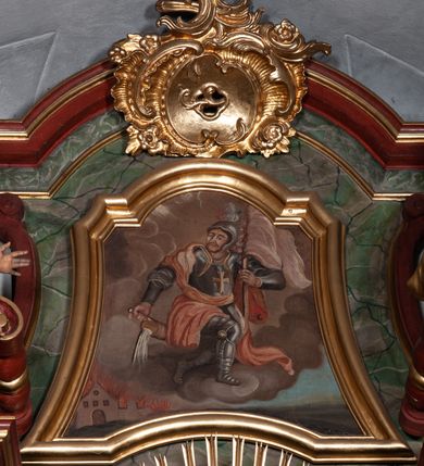 Zdjęcie nr 28: Retabulum jednokondygnacyjne, trójosiowe ze zwieńczeniem i bramkami. Mensa ołtarzowa z malowanym antepedium przedstawiającym scenę Ostatniej Wieczerzy według Leonarda da Vinci. Na mensie ustawione pozłacane tabernakulum w formie prostopadłościennej z częścią środkową w ozdobnej oprawie utworzonej przez dwa ukośnie dostawione filary ze spływami wolutowymi. Między nimi wypukłe w dolnej części drzwiczki dekorowane kielichem z hostią ponad kiśćmi winogron i między kłosami zbóż. Powyżej nisza konchowa wypełniona glorią, której koncha ozdobiona jest muszlą z rocaille’owym grzebieniem. Na wolutach osadzone adorujące krzyż putta. Część centralna nastawy flankowana kolumnami z głowicami jońskimi i ornamentem rokokowym. W polu w profilowanej złotej ramie przedstawienie koronacji Marii przez Trójcę Świętą. Drewniana konstrukcja skrzydeł bocznych tworzy ramę dla dwóch rzeźb ustawionych na bramkach, na odcinkach gzymsu rozszerzających się ku górze, które tworzą cokoły ozdobione w dolnej części rokokową muszlą. Po prawej stronie znajduje się rzeźba przedstawiająca św. Stanisława z Piotrowinem, po lewej św. Wojciecha. Obie rzeźby biskupów są tej samej wielkości, wypełniają prześwity w bocznych skrzydłach, w tle ozdobionych rocaille’owym ornamentem. Zewnętrzne płaszczyzny skrzydeł bocznych zdobi złota winorośl, a wewnętrzne ornament roślinny z motywem kwiatowym. Na kolumnach ustawionych na niewielkich cokołach wspiera się przełamane belkowanie zakończone gzymsem dźwigającym odcinkowy przyczółek z profilowaniem zakończonym wolutami. Na wysokości belkowania znajduje się płaskorzeźba przedstawiająca Boga Ojca i Ducha Świętego pod postacią gołębicy, wyłaniających się ze srebrnych obłoków; postacie otoczone są złotymi promieniami. Na bocznych osiach, analogicznie pojawiają się srebrne chmury o wolutowych kształtach, flankowane przez anielskie główki. Zwieńczenie rozszerza się ku górze i jest zamknięte łukiem nadwieszonym; znajduje się w nim obraz przedstawiający św. Floriana w profilowanej, złoconej wklęsło-wypukłej ramie. Całość zwieńczona kartuszem utworzonym z ornamentu rocaille’owego. Struktura polichromowana imitacją marmoryzacji w kolorze szarym i zielonym, fryzy i gzymsy bordowe i ciemnozielone, profile, ornamenty, kolumny złocone, dekoracje złocone i srebrzone. 