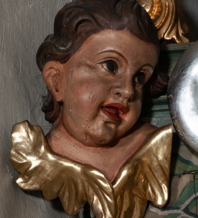 Zdjęcie nr 48: Retabulum jednokondygnacyjne, trójosiowe ze zwieńczeniem i bramkami. Mensa ołtarzowa z malowanym antepedium przedstawiającym scenę Ostatniej Wieczerzy według Leonarda da Vinci. Na mensie ustawione pozłacane tabernakulum w formie prostopadłościennej z częścią środkową w ozdobnej oprawie utworzonej przez dwa ukośnie dostawione filary ze spływami wolutowymi. Między nimi wypukłe w dolnej części drzwiczki dekorowane kielichem z hostią ponad kiśćmi winogron i między kłosami zbóż. Powyżej nisza konchowa wypełniona glorią, której koncha ozdobiona jest muszlą z rocaille’owym grzebieniem. Na wolutach osadzone adorujące krzyż putta. Część centralna nastawy flankowana kolumnami z głowicami jońskimi i ornamentem rokokowym. W polu w profilowanej złotej ramie przedstawienie koronacji Marii przez Trójcę Świętą. Drewniana konstrukcja skrzydeł bocznych tworzy ramę dla dwóch rzeźb ustawionych na bramkach, na odcinkach gzymsu rozszerzających się ku górze, które tworzą cokoły ozdobione w dolnej części rokokową muszlą. Po prawej stronie znajduje się rzeźba przedstawiająca św. Stanisława z Piotrowinem, po lewej św. Wojciecha. Obie rzeźby biskupów są tej samej wielkości, wypełniają prześwity w bocznych skrzydłach, w tle ozdobionych rocaille’owym ornamentem. Zewnętrzne płaszczyzny skrzydeł bocznych zdobi złota winorośl, a wewnętrzne ornament roślinny z motywem kwiatowym. Na kolumnach ustawionych na niewielkich cokołach wspiera się przełamane belkowanie zakończone gzymsem dźwigającym odcinkowy przyczółek z profilowaniem zakończonym wolutami. Na wysokości belkowania znajduje się płaskorzeźba przedstawiająca Boga Ojca i Ducha Świętego pod postacią gołębicy, wyłaniających się ze srebrnych obłoków; postacie otoczone są złotymi promieniami. Na bocznych osiach, analogicznie pojawiają się srebrne chmury o wolutowych kształtach, flankowane przez anielskie główki. Zwieńczenie rozszerza się ku górze i jest zamknięte łukiem nadwieszonym; znajduje się w nim obraz przedstawiający św. Floriana w profilowanej, złoconej wklęsło-wypukłej ramie. Całość zwieńczona kartuszem utworzonym z ornamentu rocaille’owego. Struktura polichromowana imitacją marmoryzacji w kolorze szarym i zielonym, fryzy i gzymsy bordowe i ciemnozielone, profile, ornamenty, kolumny złocone, dekoracje złocone i srebrzone. 