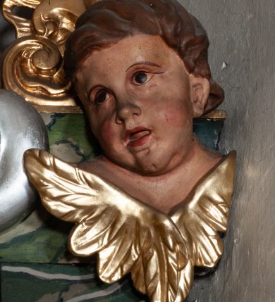 Zdjęcie nr 45: Retabulum jednokondygnacyjne, trójosiowe ze zwieńczeniem i bramkami. Mensa ołtarzowa z malowanym antepedium przedstawiającym scenę Ostatniej Wieczerzy według Leonarda da Vinci. Na mensie ustawione pozłacane tabernakulum w formie prostopadłościennej z częścią środkową w ozdobnej oprawie utworzonej przez dwa ukośnie dostawione filary ze spływami wolutowymi. Między nimi wypukłe w dolnej części drzwiczki dekorowane kielichem z hostią ponad kiśćmi winogron i między kłosami zbóż. Powyżej nisza konchowa wypełniona glorią, której koncha ozdobiona jest muszlą z rocaille’owym grzebieniem. Na wolutach osadzone adorujące krzyż putta. Część centralna nastawy flankowana kolumnami z głowicami jońskimi i ornamentem rokokowym. W polu w profilowanej złotej ramie przedstawienie koronacji Marii przez Trójcę Świętą. Drewniana konstrukcja skrzydeł bocznych tworzy ramę dla dwóch rzeźb ustawionych na bramkach, na odcinkach gzymsu rozszerzających się ku górze, które tworzą cokoły ozdobione w dolnej części rokokową muszlą. Po prawej stronie znajduje się rzeźba przedstawiająca św. Stanisława z Piotrowinem, po lewej św. Wojciecha. Obie rzeźby biskupów są tej samej wielkości, wypełniają prześwity w bocznych skrzydłach, w tle ozdobionych rocaille’owym ornamentem. Zewnętrzne płaszczyzny skrzydeł bocznych zdobi złota winorośl, a wewnętrzne ornament roślinny z motywem kwiatowym. Na kolumnach ustawionych na niewielkich cokołach wspiera się przełamane belkowanie zakończone gzymsem dźwigającym odcinkowy przyczółek z profilowaniem zakończonym wolutami. Na wysokości belkowania znajduje się płaskorzeźba przedstawiająca Boga Ojca i Ducha Świętego pod postacią gołębicy, wyłaniających się ze srebrnych obłoków; postacie otoczone są złotymi promieniami. Na bocznych osiach, analogicznie pojawiają się srebrne chmury o wolutowych kształtach, flankowane przez anielskie główki. Zwieńczenie rozszerza się ku górze i jest zamknięte łukiem nadwieszonym; znajduje się w nim obraz przedstawiający św. Floriana w profilowanej, złoconej wklęsło-wypukłej ramie. Całość zwieńczona kartuszem utworzonym z ornamentu rocaille’owego. Struktura polichromowana imitacją marmoryzacji w kolorze szarym i zielonym, fryzy i gzymsy bordowe i ciemnozielone, profile, ornamenty, kolumny złocone, dekoracje złocone i srebrzone. 