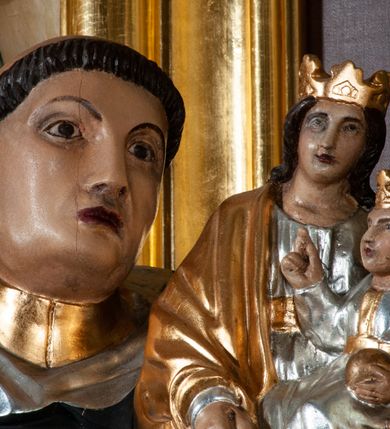 Zdjęcie nr 6: Rzeźba pełna na cokole. Święty Jacek wyobrażony w całej postaci, stojący frontalnie, w kontrapoście, z lewą nogą wysuniętą do przodu. Obie ręce zgięte w łokciach, w prawej trzyma kij, w lewej figurkę Matki Boskiej z Dzieciątkiem w srebrnych i złotych szatach. Twarz podłużna, oczy małe, nos prosty, usta szerokie, ciemnoczerwone. Głowa otoczona krótkimi, brązowymi włosami z wyciętą tonsurą. Święty ubrany jest w srebrny habit ze złotym szkaplerzem i czarny płaszcz z kapturem, spod ubrania widoczne czubki czarnych butów. Polichromia w odsłoniętych partiach karnacji traktowana naturalistyczne. 