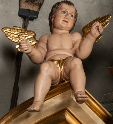 Zdjęcie nr 14: Ołtarz jednokondygnacyjny, jednoosiowy, na wysokim cokole, ze zwieńczeniem w formie glorii. Mensa ołtarzowa w kształcie prostopadłościanu, antepedium w postaci leżącego prostokąta, tkane, dekorowane rzędem maków w dolnej partii. Kondygnacja nastawy flankowana przez zwielokrotnione pilastry, ozdobione z zewnętrznych stron ornamentami roślinnymi i wysuniętymi przed nie kolumnami z głowicami kompozytowymi, ozdobionymi wolutami i liśćmi akantu. Kolumny i pilastry ustawione na wysokim cokole dekorowanym płycinami, dźwigają rozbudowane belkowanie, w pasie fryzu dekorowane rozetami. Belkowanie przełamuje się nad zwielokrotnionymi pilastrami i kolumnami i podtrzymuje fragment przerwanego przyczółka, na którym siedzą dwa putta. W polu znajduje się wnęka w kształcie stojącego prostokąta o górnych narożach wklęsłych, w której umieszczono krucyfiks. Zwieńczenie tworzy gloria promienista z centralnie umieszczonym okiem Opatrzności w otoku z obłoków i główek anielskich. Struktura polichromowana, marmoryzowana w odcieniu kremowym, kolumny, ornamenty i profile złocone, płyciny bordowe, gloria srebrzona i złocona.  