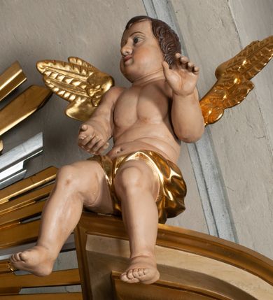 Zdjęcie nr 3: Ołtarz jednokondygnacyjny, jednoosiowy, na wysokim cokole, ze zwieńczeniem w formie glorii. Mensa ołtarzowa w kształcie prostopadłościanu, antepedium w postaci leżącego prostokąta, tkane, dekorowane rzędem maków w dolnej partii. Kondygnacja nastawy flankowana przez zwielokrotnione pilastry, ozdobione z zewnętrznych stron ornamentami roślinnymi i wysuniętymi przed nie kolumnami z głowicami kompozytowymi, ozdobionymi wolutami i liśćmi akantu. Kolumny i pilastry ustawione na wysokim cokole dekorowanym płycinami, dźwigają rozbudowane belkowanie, w pasie fryzu dekorowane rozetami. Belkowanie przełamuje się nad zwielokrotnionymi pilastrami i kolumnami i podtrzymuje fragment przerwanego przyczółka, na którym siedzą dwa putta. W polu znajduje się wnęka w kształcie stojącego prostokąta o górnych narożach wklęsłych, w której umieszczono krucyfiks. Zwieńczenie tworzy gloria promienista z centralnie umieszczonym okiem Opatrzności w otoku z obłoków i główek anielskich. Struktura polichromowana, marmoryzowana w odcieniu kremowym, kolumny, ornamenty i profile złocone, płyciny bordowe, gloria srebrzona i złocona.  