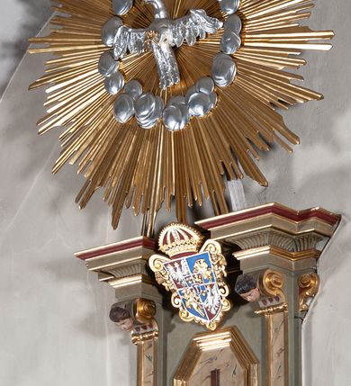 Zdjęcie nr 10: Ambona przyścienna, wisząca, dostępna od strony prezbiterium. Kosz na planie wklęsło-wypukłym, na  zwężającym się cokole dekorowanym liśćmi. U spodu podwieszone dekorowane rocaille’m woluty podtrzymujące szyszkę. Ścianki kosza wklęsłe, zdobione  płycinami wypełnionymi główkami anielskimi, a ścięte naroża wolutami z rocaille’m i główkami anielskimi. Kosz zamknięty parapetem w formie belkowania, wyłamanego na narożach. Z prawej strony do kosza prowadzą schody z ażurową balustradą wyciętą w pionowe, fantazyjne kształty, z poręczą. Zaplecek w kształcie stojącego prostokąta flankowany pilastrami wypełnionymi płycinami z głowicami utworzonymi z wolut i główek anielskich, podtrzymującymi fragmenty pełnego, wyłamanego na ich osiach belkowania. W polu płycina w kształcie stojącego prostokąta o ściętych górnych narożach z krucyfiksem. Nad nią, między fragmentami belkowania pięciopolowy herb Wazów zwieńczony koroną. Ponad zapleckiem płaskorzeźbiona gołębica Ducha Świętego w otoku z obłoków na tle dużych rozmiarów glorii promienistej. 
Struktura polichromowana w kolorze zielonym; płyciny marmoryzowane w odcieniu jasnego brązu; profilowania brązowe, detale, ornamenty, gloria złocone, gołębica i obłoki srebrzone. 
