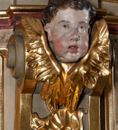 Zdjęcie nr 13: Ambona przyścienna, wisząca, dostępna od strony prezbiterium. Kosz na planie wklęsło-wypukłym, na  zwężającym się cokole dekorowanym liśćmi. U spodu podwieszone dekorowane rocaille’m woluty podtrzymujące szyszkę. Ścianki kosza wklęsłe, zdobione  płycinami wypełnionymi główkami anielskimi, a ścięte naroża wolutami z rocaille’m i główkami anielskimi. Kosz zamknięty parapetem w formie belkowania, wyłamanego na narożach. Z prawej strony do kosza prowadzą schody z ażurową balustradą wyciętą w pionowe, fantazyjne kształty, z poręczą. Zaplecek w kształcie stojącego prostokąta flankowany pilastrami wypełnionymi płycinami z głowicami utworzonymi z wolut i główek anielskich, podtrzymującymi fragmenty pełnego, wyłamanego na ich osiach belkowania. W polu płycina w kształcie stojącego prostokąta o ściętych górnych narożach z krucyfiksem. Nad nią, między fragmentami belkowania pięciopolowy herb Wazów zwieńczony koroną. Ponad zapleckiem płaskorzeźbiona gołębica Ducha Świętego w otoku z obłoków na tle dużych rozmiarów glorii promienistej. 
Struktura polichromowana w kolorze zielonym; płyciny marmoryzowane w odcieniu jasnego brązu; profilowania brązowe, detale, ornamenty, gloria złocone, gołębica i obłoki srebrzone. 

