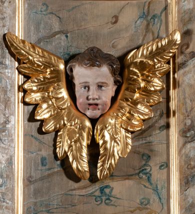 Zdjęcie nr 15: Ambona przyścienna, wisząca, dostępna od strony prezbiterium. Kosz na planie wklęsło-wypukłym, na  zwężającym się cokole dekorowanym liśćmi. U spodu podwieszone dekorowane rocaille’m woluty podtrzymujące szyszkę. Ścianki kosza wklęsłe, zdobione  płycinami wypełnionymi główkami anielskimi, a ścięte naroża wolutami z rocaille’m i główkami anielskimi. Kosz zamknięty parapetem w formie belkowania, wyłamanego na narożach. Z prawej strony do kosza prowadzą schody z ażurową balustradą wyciętą w pionowe, fantazyjne kształty, z poręczą. Zaplecek w kształcie stojącego prostokąta flankowany pilastrami wypełnionymi płycinami z głowicami utworzonymi z wolut i główek anielskich, podtrzymującymi fragmenty pełnego, wyłamanego na ich osiach belkowania. W polu płycina w kształcie stojącego prostokąta o ściętych górnych narożach z krucyfiksem. Nad nią, między fragmentami belkowania pięciopolowy herb Wazów zwieńczony koroną. Ponad zapleckiem płaskorzeźbiona gołębica Ducha Świętego w otoku z obłoków na tle dużych rozmiarów glorii promienistej. 
Struktura polichromowana w kolorze zielonym; płyciny marmoryzowane w odcieniu jasnego brązu; profilowania brązowe, detale, ornamenty, gloria złocone, gołębica i obłoki srebrzone. 
