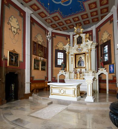 Zdjęcie nr 5: Ołtarz architektoniczny, drewniany, jednoosiowy, jednokondygnacyjny z bramkami. Mensa wąska, prostopadłościenna o ściankach wklęsło-wypukłych. Tabernakulum w kształcie prostopadłościennej skrzynki z przodu o linii wklęsło-wypukłej z uskokami. Ustawione jest na  wysokim cokole, flankowane parą szerokich, wklęsłych pilastrów, zdobionych ornamentem złożonym z przeplatających się wolut i kampanul. Ścianka frontowa wypukła, w polu prostokątne, metalowe drzwiczki, zdobione kiśćmi winogron i kłosami zbóż, pośrodku łaciński prosty krzyż. Całość zamknięta profilowanym gzymsem. Po bokach tabernakulum zwisy z kampanul, a na skrajach płaskorzeźbione uszy z liści akantu.  Do górnej krawędzi przybite gwoździem na trzech tulejach lampki oliwne. Nad tabernakulum tron wystawienia z rzeźbionymi w drewnie aniołkami na obłokach adorującymi krucyfiks. 

Retabulum ustawione na zdwojonym cokole, ujęte zwielokrotnionymi pilastrami toskańskimi i dwiema kolumnami kompozytowymi na wysokich cokołach, ustawionymi pod kątem i podtrzymującymi profilowane, przerwane belkowanie. Pilastry od strony wewnętrznej ołtarza są wklęsłe, ozdobione dwiema parami uskrzydlonych główek anielskich i zwisami z kwiatów; od zewnątrz pilastry mają trzony wypukłe.  W polu głównym wnęka, ujęta ramą w kształcie stojącego prostokąta o uszatych narożach. We wnęce na czerwonym tle umieszczony obraz Matki Boskiej Piekarskiej, na zasuwach obrazy „Koronacja Matki Boskiej” oraz „Św. Mikołaj”. Nad obrazem kartusz o kształcie zbliżonym do rombu z ornamentami rocaille&#039;owymi wokół; w polu napis „ALTARE / PRIVILEGI/ATUM”. Na osi kolumn, na przyczółku ustawione są wazony z kwiatami. 

Zwieńczenie w kształcie stojącego prostokąta, flankowane parą pilastrów podtrzymujących przerwane belkowanie, zamknięte gzymsem w formie łuku odcinkowego. Na szczycie promienista gloria z otokiem chmur pośrodku z płaskorzeźbionym monogramem IHS. W polu głównym obraz przedstawiający Ekstazę św. Teresy w kształcie stojącego prostokąta, zamknięty łukiem nadwieszonym. Po bokach zwieńczenia uszy z liści akantu i kwiatów. Pod obrazem uskrzydlona para główek aniołków. 

Bramki w formie stojącego prostokąta, flankowane węgarami, zamknięte wolutowym łukiem z ustawionymi na szczycie na niskich cokołach rzeźbami świętych: po lewej św. Piotra, a po prawej św. Pawła.  Przejście zamknięte łukiem wklęsło-wypukłym z uskokami. Struktura polichromowana w kolorze jasnobeżowym, ornamentyka złocona, detale srebrzone.
