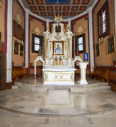 Zdjęcie nr 17: Ołtarz architektoniczny, drewniany, jednoosiowy, jednokondygnacyjny z bramkami. Mensa wąska, prostopadłościenna o ściankach wklęsło-wypukłych. Tabernakulum w kształcie prostopadłościennej skrzynki z przodu o linii wklęsło-wypukłej z uskokami. Ustawione jest na  wysokim cokole, flankowane parą szerokich, wklęsłych pilastrów, zdobionych ornamentem złożonym z przeplatających się wolut i kampanul. Ścianka frontowa wypukła, w polu prostokątne, metalowe drzwiczki, zdobione kiśćmi winogron i kłosami zbóż, pośrodku łaciński prosty krzyż. Całość zamknięta profilowanym gzymsem. Po bokach tabernakulum zwisy z kampanul, a na skrajach płaskorzeźbione uszy z liści akantu.  Do górnej krawędzi przybite gwoździem na trzech tulejach lampki oliwne. Nad tabernakulum tron wystawienia z rzeźbionymi w drewnie aniołkami na obłokach adorującymi krucyfiks. 

Retabulum ustawione na zdwojonym cokole, ujęte zwielokrotnionymi pilastrami toskańskimi i dwiema kolumnami kompozytowymi na wysokich cokołach, ustawionymi pod kątem i podtrzymującymi profilowane, przerwane belkowanie. Pilastry od strony wewnętrznej ołtarza są wklęsłe, ozdobione dwiema parami uskrzydlonych główek anielskich i zwisami z kwiatów; od zewnątrz pilastry mają trzony wypukłe.  W polu głównym wnęka, ujęta ramą w kształcie stojącego prostokąta o uszatych narożach. We wnęce na czerwonym tle umieszczony obraz Matki Boskiej Piekarskiej, na zasuwach obrazy „Koronacja Matki Boskiej” oraz „Św. Mikołaj”. Nad obrazem kartusz o kształcie zbliżonym do rombu z ornamentami rocaille'owymi wokół; w polu napis „ALTARE / PRIVILEGI/ATUM”. Na osi kolumn, na przyczółku ustawione są wazony z kwiatami. 

Zwieńczenie w kształcie stojącego prostokąta, flankowane parą pilastrów podtrzymujących przerwane belkowanie, zamknięte gzymsem w formie łuku odcinkowego. Na szczycie promienista gloria z otokiem chmur pośrodku z płaskorzeźbionym monogramem IHS. W polu głównym obraz przedstawiający Ekstazę św. Teresy w kształcie stojącego prostokąta, zamknięty łukiem nadwieszonym. Po bokach zwieńczenia uszy z liści akantu i kwiatów. Pod obrazem uskrzydlona para główek aniołków. 

Bramki w formie stojącego prostokąta, flankowane węgarami, zamknięte wolutowym łukiem z ustawionymi na szczycie na niskich cokołach rzeźbami świętych: po lewej św. Piotra, a po prawej św. Pawła.  Przejście zamknięte łukiem wklęsło-wypukłym z uskokami. Struktura polichromowana w kolorze jasnobeżowym, ornamentyka złocona, detale srebrzone.
