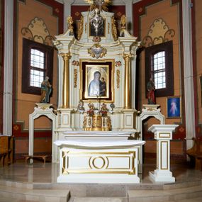 Zdjęcie nr 1: Ołtarz architektoniczny, drewniany, jednoosiowy, jednokondygnacyjny z bramkami. Mensa wąska, prostopadłościenna o ściankach wklęsło-wypukłych. Tabernakulum w kształcie prostopadłościennej skrzynki z przodu o linii wklęsło-wypukłej z uskokami. Ustawione jest na  wysokim cokole, flankowane parą szerokich, wklęsłych pilastrów, zdobionych ornamentem złożonym z przeplatających się wolut i kampanul. Ścianka frontowa wypukła, w polu prostokątne, metalowe drzwiczki, zdobione kiśćmi winogron i kłosami zbóż, pośrodku łaciński prosty krzyż. Całość zamknięta profilowanym gzymsem. Po bokach tabernakulum zwisy z kampanul, a na skrajach płaskorzeźbione uszy z liści akantu.  Do górnej krawędzi przybite gwoździem na trzech tulejach lampki oliwne. Nad tabernakulum tron wystawienia z rzeźbionymi w drewnie aniołkami na obłokach adorującymi krucyfiks. 

Retabulum ustawione na zdwojonym cokole, ujęte zwielokrotnionymi pilastrami toskańskimi i dwiema kolumnami kompozytowymi na wysokich cokołach, ustawionymi pod kątem i podtrzymującymi profilowane, przerwane belkowanie. Pilastry od strony wewnętrznej ołtarza są wklęsłe, ozdobione dwiema parami uskrzydlonych główek anielskich i zwisami z kwiatów; od zewnątrz pilastry mają trzony wypukłe.  W polu głównym wnęka, ujęta ramą w kształcie stojącego prostokąta o uszatych narożach. We wnęce na czerwonym tle umieszczony obraz Matki Boskiej Piekarskiej, na zasuwach obrazy „Koronacja Matki Boskiej” oraz „Św. Mikołaj”. Nad obrazem kartusz o kształcie zbliżonym do rombu z ornamentami rocaille'owymi wokół; w polu napis „ALTARE / PRIVILEGI/ATUM”. Na osi kolumn, na przyczółku ustawione są wazony z kwiatami. 

Zwieńczenie w kształcie stojącego prostokąta, flankowane parą pilastrów podtrzymujących przerwane belkowanie, zamknięte gzymsem w formie łuku odcinkowego. Na szczycie promienista gloria z otokiem chmur pośrodku z płaskorzeźbionym monogramem IHS. W polu głównym obraz przedstawiający Ekstazę św. Teresy w kształcie stojącego prostokąta, zamknięty łukiem nadwieszonym. Po bokach zwieńczenia uszy z liści akantu i kwiatów. Pod obrazem uskrzydlona para główek aniołków. 

Bramki w formie stojącego prostokąta, flankowane węgarami, zamknięte wolutowym łukiem z ustawionymi na szczycie na niskich cokołach rzeźbami świętych: po lewej św. Piotra, a po prawej św. Pawła.  Przejście zamknięte łukiem wklęsło-wypukłym z uskokami. Struktura polichromowana w kolorze jasnobeżowym, ornamentyka złocona, detale srebrzone.
