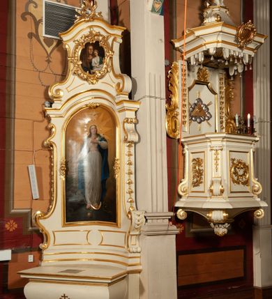 Zdjęcie nr 3: Ołtarz jednoosiowy, jednokondygnacyjny ze zwieńczeniem. Mensa w typie sarkofagowym, z monogramem maryjnym na ścianie frontowej. Nastawa ołtarzowa na cokole o wklęsłym rzucie, zwężająca się ku górze, ujęta po bokach szerokimi spływami wolutowymi, zdobionymi zwisami z kampanul, a w dolnej części cekinami. W polu ołtarza obraz Matki Boskiej Niepokalanie Poczętej w złoconej ramie o kształcie prostokąta stojącego, zamkniętego łukiem półkolistym. Kondygnację zamyka profilowany gzyms w kształcie łuku nadwieszonego. Zwieńczenie w formie zbliżonej do stojącego prostokąta, ujęte po bokach spływami wolutowymi. W polu, w kartuszowej ramie, zdobionej ornamentem rocaille’owym obraz „Nauczanie Marii”. Zwieńczenie zamknięte profilowanym gzymsem o przebiegu wklęsło-wypukłym. Na szczycie rokokowy akroterion. Ołtarz utrzymany w kolorystyce kości słoniowej ze złoceniami w partiach ornamentów i profilowań.


