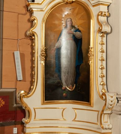 Zdjęcie nr 2: Ołtarz jednoosiowy, jednokondygnacyjny ze zwieńczeniem. Mensa w typie sarkofagowym, z monogramem maryjnym na ścianie frontowej. Nastawa ołtarzowa na cokole o wklęsłym rzucie, zwężająca się ku górze, ujęta po bokach szerokimi spływami wolutowymi, zdobionymi zwisami z kampanul, a w dolnej części cekinami. W polu ołtarza obraz Matki Boskiej Niepokalanie Poczętej w złoconej ramie o kształcie prostokąta stojącego, zamkniętego łukiem półkolistym. Kondygnację zamyka profilowany gzyms w kształcie łuku nadwieszonego. Zwieńczenie w formie zbliżonej do stojącego prostokąta, ujęte po bokach spływami wolutowymi. W polu, w kartuszowej ramie, zdobionej ornamentem rocaille’owym obraz „Nauczanie Marii”. Zwieńczenie zamknięte profilowanym gzymsem o przebiegu wklęsło-wypukłym. Na szczycie rokokowy akroterion. Ołtarz utrzymany w kolorystyce kości słoniowej ze złoceniami w partiach ornamentów i profilowań.


