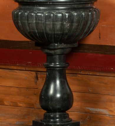 Zdjęcie nr 2: Chrzcielnica osadzona na wysokim, prostopadłościennym cokole, z trzonem w typie gruszkowym oraz czarą z puklami i profilowanym brzegiem. Pokrywa w kształcie ażurowej świątynki, na rzucie czworoboku, ujętej spływami wolutowymi, nakryta czworoboczną kopułką z krzyżem; wewnątrz św. Jana Chrzciciel chrzczący Jezusa w Jordanie. 

