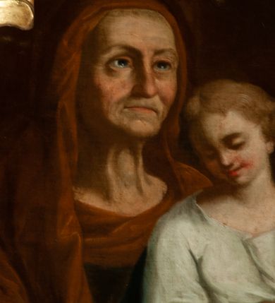 Zdjęcie nr 2: Obraz w kształcie zbliżonym do owalu, ujęty kartuszową, rocaille'ową ramą o nieregularnym, wewnętrznym obrysie ograniczającym pole obrazu. Na jednolitym ciemnym tle św. Anna, ukazana w półpostaci, z twarzą zwróconą w lewą stronę, trzymająca na kolanach młodzieńczą Marię, przedstawioną w trzech czwartych postaci. Święta Anna wyobrażona jako starsza kobieta o pokrytej zmarszczkami twarzy, ze wzrokiem wpatrzonym w dal. Jest ubrana w granatową suknię z długimi rękawami oraz brunatny welon założony na głowę i spływający na ramiona. Maria ubrana w białą sukienkę z podwiniętymi rękawami, przewiązaną w pasie złotym paskiem oraz w niebieski płaszcz założony na lewe ramię. Ma jasne włosy, średniej długości, przedzielone pośrodku przedziałkiem i młodzieńczą twarz. Maria w rękach trzyma otwartą księgę i prawą dłonią wskazuje na czytany tekst. Kolorystyka obrazu ciemna, najjaśniejszym akcentem jest szata Marii i księga.