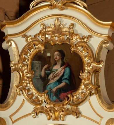 Zdjęcie nr 4: Obraz w kształcie zbliżonym do owalu, ujęty kartuszową, rocaille&#039;ową ramą o nieregularnym, wewnętrznym obrysie ograniczającym pole obrazu. W centrum kompozycji ukazana św. Barbara w trzech czwartych, zwrócona w prawo, w prawej ręce trzyma kielich z hostią, a w lewej  miecz. Twarz owalna, z drobnymi ustami, wzrok skierowany ku górze, pucułowate policzki. Ubrana jest w bogate szaty: błękitną suknię z rękawami zakończonymi falbaną, z dużym dekoltem oraz w różowoczerwony płaszcz. Włosy długie, upięte do tyłu, z puklami opadającymi na ramiona. Po lewej stronie obrazu wieża z trzema oknami. Tło jednolite, brunatne. Kolorystka pierwszego planu żywa, tło stonowane.