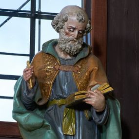 Zdjęcie nr 1: Rzeźba ustawiona na ośmiobocznej podstawie, wolnostojąca, pełnoplastyczna. Święty ukazany całej postaci, stojący, z głową skłonioną delikatnie w dół, w kierunku trzymanej w lewej dłoni otwartej księgi; w prawej trzyma złoty klucz. Twarz szeroka, o rysach starszego mężczyzny, okolona bujną, siwą, średniej długości brodą. Na głowie łysina oraz kępka włosów nad czołem. Święty ubrany w długą, fioletową suknię z długimi rękawami, przewiązaną złotym paskiem oraz brązowy płaszcz z zieloną podszewką, spięty na piersi, dekorowany na brzegach lamówką pokrytą roślinnym ornamentem; na nogach sandały. Polichromia w odsłoniętych partiach ciała naturalistyczna. 

