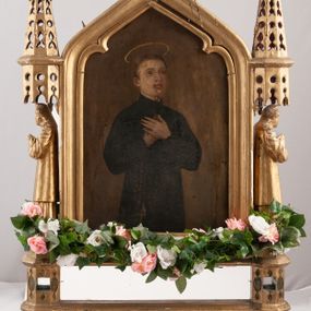 Zdjęcie nr 1: Feretron dwustronny z obrazami św. Stanisława Kostki oraz Anioła Stróża. Konstrukcja feretronu osadzona na dwóch nóżkach na planie koła, wspierających dwa wieloboczne w rzucie cokoły, połączone listwami stabilizującymi konstrukcję feretronu; cokoły zaopatrzone w otwory na drążki do noszenia. Na cokołach ustawione dwie rzeźby niezidentyfikowanych świętych, ujętych z profilu, nad nimi nadwieszone baldachimy zwieńczone stylizowanymi kwiatonami. W centrum tej konstrukcji obrazy ujęte w profilowaną ramę, zamkniętą łukiem ostrym o spłaszczonych ramionach, zwieńczoną krzyżykiem łacińskim o trójlistnie zakończonych ramionach. Struktura feretronu złocona. Na obrazie Anioł Stróż  ukazany jest po prawej stronie kompozycji, w postawie stojącej, widoczny z lewego profilu, pochylony nad dzieckiem bawiącym się na kwietnej łące. Ubrany jest w białą, długą sukienkę. Tło obrazu jednolite, ciemnoniebieskie. Po drugiej stronie feretronu znajduje się wizerunek św. Stanisława Kostki. Święty ukazany do kolan, stojący frontalnie, delikatnie zwrócony w lewo, z rękami złożonymi na piersi, z różańcem w dłoniach. Twarz szeroka, ze wzrokiem skierowanym ku górze, włosy krótkie i jasnobrązowe. Święty ubrany jest w sutannę jezuicką. Wokół głowy ma złoty, okrągły nimb. Tło obrazu jednolite, brązowe.
