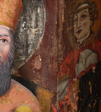 Zdjęcie nr 8: Rzeźba pełnoplastyczna, przyścienna, ścięta z tyłu; całopostaciowe przedstawienie stojącego na niewysokim postumencie św. Mikołaja. Święty ukazany frontalnie. Twarz pociągła, o wyrazistych rysach i długim, brązowym zaroście, włosy sięgające szyi. Święty w stroju pontyfikalnym: ubrany w długą, białą albę oraz jasnoczerwoną dalmatykę lub tunicelę i ornat sięgający do połowy łydek. Na głowie infuła biskupia. W lewej ręce prostopadłościenna skrzyneczka z napisem: IHS i trzema złotymi kulami, w prawej pastorał. Figura umieszczona w prostopadłościennej szafie oltarzowej o skośnych ścianach bocznych zdobionych figuralną polichromią. Po lewej stronie św. Wawrzyniec, po prawej św. Szczepan, na wysokości głowy świętego polichromowana, jasna aureola.