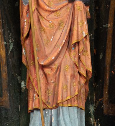 Zdjęcie nr 6: Rzeźba pełnoplastyczna, przyścienna, ścięta z tyłu; całopostaciowe przedstawienie stojącego na niewysokim postumencie św. Mikołaja. Święty ukazany frontalnie. Twarz pociągła, o wyrazistych rysach i długim, brązowym zaroście, włosy sięgające szyi. Święty w stroju pontyfikalnym: ubrany w długą, białą albę oraz jasnoczerwoną dalmatykę lub tunicelę i ornat sięgający do połowy łydek. Na głowie infuła biskupia. W lewej ręce prostopadłościenna skrzyneczka z napisem: IHS i trzema złotymi kulami, w prawej pastorał. Figura umieszczona w prostopadłościennej szafie oltarzowej o skośnych ścianach bocznych zdobionych figuralną polichromią. Po lewej stronie św. Wawrzyniec, po prawej św. Szczepan, na wysokości głowy świętego polichromowana, jasna aureola.