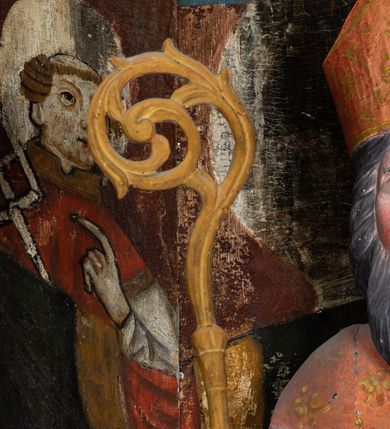 Zdjęcie nr 7: Rzeźba pełnoplastyczna, przyścienna, ścięta z tyłu; całopostaciowe przedstawienie stojącego na niewysokim postumencie św. Mikołaja. Święty ukazany frontalnie. Twarz pociągła, o wyrazistych rysach i długim, brązowym zaroście, włosy sięgające szyi. Święty w stroju pontyfikalnym: ubrany w długą, białą albę oraz jasnoczerwoną dalmatykę lub tunicelę i ornat sięgający do połowy łydek. Na głowie infuła biskupia. W lewej ręce prostopadłościenna skrzyneczka z napisem: IHS i trzema złotymi kulami, w prawej pastorał. Figura umieszczona w prostopadłościennej szafie oltarzowej o skośnych ścianach bocznych zdobionych figuralną polichromią. Po lewej stronie św. Wawrzyniec, po prawej św. Szczepan, na wysokości głowy świętego polichromowana, jasna aureola.