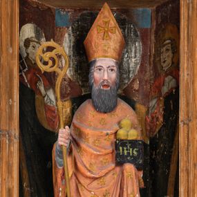 Zdjęcie nr 1: Rzeźba pełnoplastyczna, przyścienna, ścięta z tyłu; całopostaciowe przedstawienie stojącego na niewysokim postumencie św. Mikołaja. Święty ukazany frontalnie. Twarz pociągła, o wyrazistych rysach i długim, brązowym zaroście, włosy sięgające szyi. Święty w stroju pontyfikalnym: ubrany w długą, białą albę oraz jasnoczerwoną dalmatykę lub tunicelę i ornat sięgający do połowy łydek. Na głowie infuła biskupia. W lewej ręce prostopadłościenna skrzyneczka z napisem: IHS i trzema złotymi kulami, w prawej pastorał. Figura umieszczona w prostopadłościennej szafie oltarzowej o skośnych ścianach bocznych zdobionych figuralną polichromią. Po lewej stronie św. Wawrzyniec, po prawej św. Szczepan, na wysokości głowy świętego polichromowana, jasna aureola.