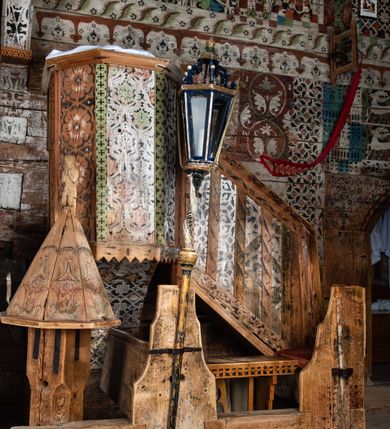 Zdjęcie nr 2: Kosz ambony na rzucie połowy ośmioboku, opięty prostymi listwami, dołem z wydzielonym cokołem z motywem ząbków, zwieńczony gzymsem. Kosz zawieszony na północnej ścianie prezbiterium na ostrosłupowej konsoli. Dostępny od wschodu, od strony wejścia do zakrystii, jednobiegowymi schodami z balustradą podzieloną listwami na romboidalne płyciny. Struktura zdobiona dekoracją patronową o motywach roślinno-geometrycznych.