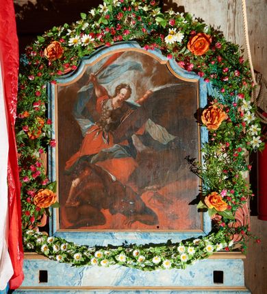 Zdjęcie nr 2: Obraz w kształcie stojącego prostokąta zwieńczonego łukiem wklęsło-wypukłym. Rama ażurowa z wici akantowej, zwieńczona główką anielską ze skrzydełkami. Obraz Matka Boska Szkaplerzna:  w kształcie stojącego prostokąta zamkniętego łukiem wklęsło-wypukłym. Pośrodku Matka Boska, ukazana w półpostaci, podtrzymująca stojące na obłoku Dzieciątko. Maria zwrócona en trois quarts w lewo, prawą ręką przytrzymuje stojące obok Dzieciątko. Twarz owalna o wysokim czole, wyraźne rysy wydobyte światłocieniem, rumiane policzki; duży nos, usta niewielkie, pełne. Włosy brązowe, falowane, z przedziałkiem na środku głowy, ukryte pod welonem. Ubrana w czerwoną suknię z długimi rękawami, przez ramiona przerzucony płaszcz z obfita partią drapowanej tkaniny przy prawym boku. Na głowie biały welon zarzucony na ramiona. Dzieciatko zwrócone en trois quarts w prawo, w kontrapoście, prawym łokciem opiera się ramię Matki, w lewej, wyciągniętej trzyma szkaplerz z literami: IHS. Twarz pełna o pucułowatych, rumianych policzkach, dużym czole, niewielkie oczy spoglądające w dół, zadarty nosek. Włosy krótkie, jasne, kręcone. Ciało o wydatnej muskulaturze, wydobytej światłocieniem. Przez biodra przewiązana biała pieluszka, ze zwisem tkaniny przy lewym boku. Postacie ukazane na tle kłębiastych, ciemnych chmur , rozświetlonych w górnej partii obrazu i u spodu Dzieciatka. Kolorystyka ciepła, nasycona. Plastyka wydobyta światłocieniem, o delikatnych przejściach tonalnych, ciała rozświetlone, laserunki. Obraz św. Michał Archanioł: W centrum obrazu całopostaciowe przedstawienie św. Michała Archanioła pokonującego szatana. Archanioł zwrócony en trois quarts w lewo, w dużym wykroku, w lewej ręce, przed piersią, dzierży tarczę, w prawej, uniesionej w górę, trzyma płomienisty miecz. Twarz owalna, z dużym czołem, oczy głęboko osadzone, mały nos, rumiane lica. Włosy krótkie, gęste, kręcone. Na głowie diadem. Ubrany w czerwoną, rozwianą u spodu tunikę, sięgającą kolan oraz zbroję torsową , bogato dekorowaną, z frędzlami. Postać otoczona rozwianym pasem niebieskiego, zawijającego się płaszcza. Na nogach wysokie sandały. Skrzydła duże, rozpostarte.