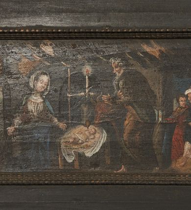 Zdjęcie nr 17: Prostokątny obraz umieszczony w predelli ołtarza, w płycinie w kształcie leżącego prostokąta z uszakami w narożach, ze sceną Bożego Narodzenia. Pośrodku żłobek z leżącym na białej tkaninie Dzieciątkiem Jezus. Po lewej stronie przyklękająca Matka Boska w ujęciu trzy czwarte, z opuszczonymi w dół, rozłożonymi rękami. Po prawej stronie żłobka stojący wykroku, ujęty w trzech czwartych św. Józef. Za żłobkiem widoczny wół i osioł, powyżej ich głów płonąca świeca. Postaci znajdują się w szopce. Po prawej stronie szopki postaci trzech króli/trzech pasterzy. Po lewej stronie szopki, w głębi, w partii pejzażu stanowiącego tło sceny, grupka pasterzy pasących trzodę, w górze postać anioła wśród obłoków. Po bokach obrazu para pól z motywami czerwonych kartuszy herbowych pośrodku; po prawej stronie godło krakowskich kanoników regularnych (?) oraz data: 1661. W polu po lewej stronie nieczytelny napis. Kolorystyka utrzymana w tonacji ciepłej, z przewagą brązów, ugrów, czerwieni, bieli, szarości barw.