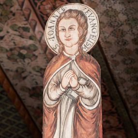 Zdjęcie nr 1: W centrum krzyż widlasty z figurą martwego Chrystusa Ukrzyżowanego; flankowany przez malowane na desce postacie Matki Boskiej i św. Jana. Obrazy w kształcie wyciętego obrysu postaci. Obraz z Matką Boską po prawej stronie krzyża. Maria zwrócona en face, z rękoma skrzyżowanymi na piersi i głową skierowaną w stronę krzyża. Twarz owalna,, o młodzieńczych rysach. Ubrana w czerwoną suknię z długimi, wąskimi rękawami ze złotą lamówką oraz biały płaszcz narzucony na głowę i ramiona, opadający falami po bokach. Wokół głowy nimb z napisem: S. MARIA ORA PRO NOBIS PECCATOR[IBUS] Obraz z przedstawieniem św. Jana po lewej stronie krzyża. Święty zwrócony en face, z dłońmi złożonymi na piersi, lewą podtrzymuje zamkniętą księgę. Twarz owalna, o pełnych policzkach i wyraźnych, młodzieńczych rysach. Włosy długie poskręcane w pukle i opadające na ramiona. Ubrany w białą tunikę o wąskich długich rękawach, drapowaną w równoległe fałdy oraz czerwony płaszcz zapięty przy szyi fibulą, opadający kaskadami na ramiona i boki. Wokół głowy nimb z napisem: S. IOANNES EVANGELISTA. Malowane płaską plamą barwną z silnym konturem.