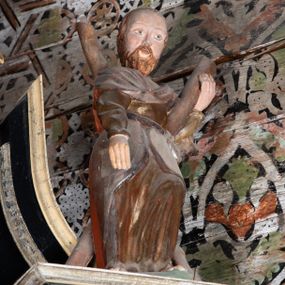 Zdjęcie nr 1: Rzeźba pełnoplastyczna, drążona, ustawiona na prostopadłościennym cokole. Święty ukazany frontalnie, w wykroku, przechylony do tyłu, opierając się o stojący na nim krzyż w kształcie litery X; lewą ręką podtrzymuje belkę, prawa pozostaje opuszczona wzdłuż ciała. Święty ubrany w złotą, drapowaną tunikę z długim rękawem oraz srebrny płaszcz przerzucony przez pierś i zawinięty na biodrze.