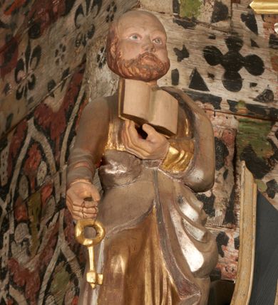 Zdjęcie nr 4: Rzeźba pełnoplastyczna, głęboko wydrążona, ustawiona na niewysokim cokole. Święty ukazany en face, w wykroku, lewą ręką podtrzymuje przy piersi otwartą księgę, w prawej, ugiętej lekko w łokciu i wyciągniętej przed siebie, trzyma klucz. Twarz pociągła, z wysokim czołem, o delikatnie rzeźbionych rysach, okolona zarostem. Ubrany w delikatnie drapowaną, złotą tunikę oraz srebrzony płaszcz zarzucony na lewe ramie i ujmujący postać po bokach spływami tkaniny.