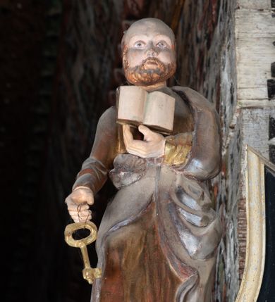 Zdjęcie nr 3: Rzeźba pełnoplastyczna, głęboko wydrążona, ustawiona na niewysokim cokole. Święty ukazany en face, w wykroku, lewą ręką podtrzymuje przy piersi otwartą księgę, w prawej, ugiętej lekko w łokciu i wyciągniętej przed siebie, trzyma klucz. Twarz pociągła, z wysokim czołem, o delikatnie rzeźbionych rysach, okolona zarostem. Ubrany w delikatnie drapowaną, złotą tunikę oraz srebrzony płaszcz zarzucony na lewe ramie i ujmujący postać po bokach spływami tkaniny.