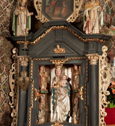 Zdjęcie nr 6: Rzeźba pełnoplastyczna, ścięta z tyłu, drążona. Święty ukazany en face, z głową przechyloną na lewe ramię. W prawej ręce trzyma pastorał, lewa wyciągnięta przed siebie. Twarz pociągła, oczy głęboko osadzone, nos prosty. Włosy  kręcone, opadające na ramiona. Ubrany w białą albę, drapowaną w sztywne, rurkowe fałdy, i skrzyżowaną na piersi stułę, przepasane w talii; oraz złoconą, sztywną kapę liturgiczną, podbitą zieloną podszewką, spiętą na piersi fibulą. Na głowie infuła biskupia o rzeźbionej dekoracji. Przy lewej nodze świętego półpostać Piotrowina, ukazanego z profilu ze złożonymi w geście modlitwy dłońmi. Polichromia naturalistyczna, atrybuty złocone.