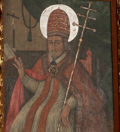 Zdjęcie nr 4: Obraz w kształcie stojącego prostokąta, w ozdobnej ramie. W centrum św. Grzegorz siedzący na tronie, ukazany do kolan, zwrócony en trois quarts w prawo; prawa ręka ugięta w łokciu z uniesioną otwartą dłonią, lewa wsparta na poręczy tronu z dłonią opuszczoną w dół podtrzymuje krzyż papieski. Twarz pociągła, o trójkątnej linii brody. Wyraźne rysy twarzy, oczy w kształcie migdałów, nos długi, prosty. Ubrany w obficie drapowaną w rurkowate fałdy rokietę o koronkowym zakończeniu rękawów. Na piersi czerwona stuła, na ramionach czerwona kapa o bogato zdobionej lamówce z przedstawieniem świętych, spięta na piersi dekoracyjną fibulą w formie kameryzowanej rozety. Na głowie tiara papieska. Wokół głowy nimb. W prawym górnym rogu obrazu podwieszona zielona kotara. W tle po lewej stronie stół z pasyjką oraz otwartą księgą. Na stole napis: S. ALEKSANDER. Kolorystyka ciemna, przytłumiona z przewagą brązów i czerwieni. Linearyzm, formy wydobyte konturem.