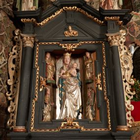 Zdjęcie nr 1: Nastawa ołtarzowa architektoniczna, jednoosiowa, jednokondygnacyjna, z wydzieloną predellą i zwieńczeniem, na cokole. Ołtarz kamienny z narzutem z tynku, sarkofagowy, wklęsło-wypukły. Mensa drewniana z portatylem z marmuru dębnickiego.Predella dekorowana płyciną w formie wydłużonego prostokąta z uszakami z malowanym przedstawieniem Bożego Narodzenia. Nastawa ujęta parą kolumn o kapitelach korynckich podtrzymujących pełne belkowanie belkowanie i gzyms, w części środkowej wyłamane ku górze trójbocznie. W polu środkowym nisza w formie stojącego prostokąta z uszakami, ujęta prostą ramą, wewnątrz gotycka szafa z figurą Matki Boskiej z Dzieciątkiem i czterech świętych dziewic. Na belkowaniu, w osi podpór figury św. Stanisława i św. Marcina (?). W zwieńczeniu ośmioboczny obraz z przedstawieniem Zwiastowania, w prostej ramie oraz bogatym obramieniu z ażurowych motywów ornamentu małżowinowo-chrząstkowego; u szczytu główka aniołka ze skrzydłami. Nastawa flankowana uszami utworzonymi z motywów ornamentu małżowinowo-chrząstkowego. W polu ponad niszą z obrazem rzeźbiona półpostać Boga Ojca. Gzyms u spodu dekorowany ornamentem małżowinowo-chrząstkowym. Struktura polichromowana na czarno, kapitele kolumn i część ornamentów srebrzone, pozostałe motywy ornamentalne złocone.