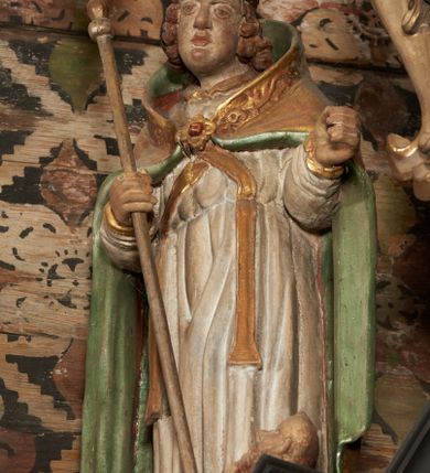 Zdjęcie nr 32: Nastawa ołtarzowa architektoniczna, jednoosiowa, jednokondygnacyjna, z wydzieloną predellą i zwieńczeniem, na cokole. Ołtarz kamienny z narzutem z tynku, sarkofagowy, wklęsło-wypukły. Mensa drewniana z portatylem z marmuru dębnickiego.Predella dekorowana płyciną w formie wydłużonego prostokąta z uszakami z malowanym przedstawieniem Bożego Narodzenia. Nastawa ujęta parą kolumn o kapitelach korynckich podtrzymujących pełne belkowanie belkowanie i gzyms, w części środkowej wyłamane ku górze trójbocznie. W polu środkowym nisza w formie stojącego prostokąta z uszakami, ujęta prostą ramą, wewnątrz gotycka szafa z figurą Matki Boskiej z Dzieciątkiem i czterech świętych dziewic. Na belkowaniu, w osi podpór figury św. Stanisława i św. Marcina (?). W zwieńczeniu ośmioboczny obraz z przedstawieniem Zwiastowania, w prostej ramie oraz bogatym obramieniu z ażurowych motywów ornamentu małżowinowo-chrząstkowego; u szczytu główka aniołka ze skrzydłami. Nastawa flankowana uszami utworzonymi z motywów ornamentu małżowinowo-chrząstkowego. W polu ponad niszą z obrazem rzeźbiona półpostać Boga Ojca. Gzyms u spodu dekorowany ornamentem małżowinowo-chrząstkowym. Struktura polichromowana na czarno, kapitele kolumn i część ornamentów srebrzone, pozostałe motywy ornamentalne złocone.