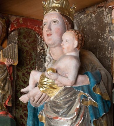 Zdjęcie nr 55: Nastawa ołtarzowa architektoniczna, jednoosiowa, jednokondygnacyjna, z wydzieloną predellą i zwieńczeniem, na cokole. Ołtarz kamienny z narzutem z tynku, sarkofagowy, wklęsło-wypukły. Mensa drewniana z portatylem z marmuru dębnickiego.Predella dekorowana płyciną w formie wydłużonego prostokąta z uszakami z malowanym przedstawieniem Bożego Narodzenia. Nastawa ujęta parą kolumn o kapitelach korynckich podtrzymujących pełne belkowanie belkowanie i gzyms, w części środkowej wyłamane ku górze trójbocznie. W polu środkowym nisza w formie stojącego prostokąta z uszakami, ujęta prostą ramą, wewnątrz gotycka szafa z figurą Matki Boskiej z Dzieciątkiem i czterech świętych dziewic. Na belkowaniu, w osi podpór figury św. Stanisława i św. Marcina (?). W zwieńczeniu ośmioboczny obraz z przedstawieniem Zwiastowania, w prostej ramie oraz bogatym obramieniu z ażurowych motywów ornamentu małżowinowo-chrząstkowego; u szczytu główka aniołka ze skrzydłami. Nastawa flankowana uszami utworzonymi z motywów ornamentu małżowinowo-chrząstkowego. W polu ponad niszą z obrazem rzeźbiona półpostać Boga Ojca. Gzyms u spodu dekorowany ornamentem małżowinowo-chrząstkowym. Struktura polichromowana na czarno, kapitele kolumn i część ornamentów srebrzone, pozostałe motywy ornamentalne złocone.