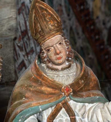 Zdjęcie nr 39: Nastawa ołtarzowa architektoniczna, jednoosiowa, jednokondygnacyjna, z wydzieloną predellą i zwieńczeniem, na cokole. Ołtarz kamienny z narzutem z tynku, sarkofagowy, wklęsło-wypukły. Mensa drewniana z portatylem z marmuru dębnickiego.Predella dekorowana płyciną w formie wydłużonego prostokąta z uszakami z malowanym przedstawieniem Bożego Narodzenia. Nastawa ujęta parą kolumn o kapitelach korynckich podtrzymujących pełne belkowanie belkowanie i gzyms, w części środkowej wyłamane ku górze trójbocznie. W polu środkowym nisza w formie stojącego prostokąta z uszakami, ujęta prostą ramą, wewnątrz gotycka szafa z figurą Matki Boskiej z Dzieciątkiem i czterech świętych dziewic. Na belkowaniu, w osi podpór figury św. Stanisława i św. Marcina (?). W zwieńczeniu ośmioboczny obraz z przedstawieniem Zwiastowania, w prostej ramie oraz bogatym obramieniu z ażurowych motywów ornamentu małżowinowo-chrząstkowego; u szczytu główka aniołka ze skrzydłami. Nastawa flankowana uszami utworzonymi z motywów ornamentu małżowinowo-chrząstkowego. W polu ponad niszą z obrazem rzeźbiona półpostać Boga Ojca. Gzyms u spodu dekorowany ornamentem małżowinowo-chrząstkowym. Struktura polichromowana na czarno, kapitele kolumn i część ornamentów srebrzone, pozostałe motywy ornamentalne złocone.